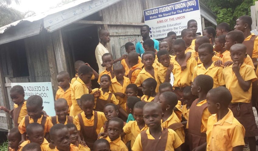 Some students and staff of Nzulezo District Assembly Primary School gathered on the school compound.