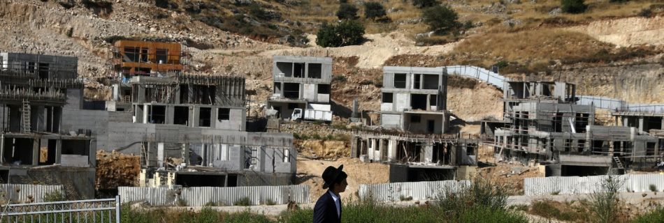 A Jewish settler walks past Israeli settlement construction sites in the Israeli-occupied West Bank near Jerusalem on June 30. (Ammar Awad/Reuters)