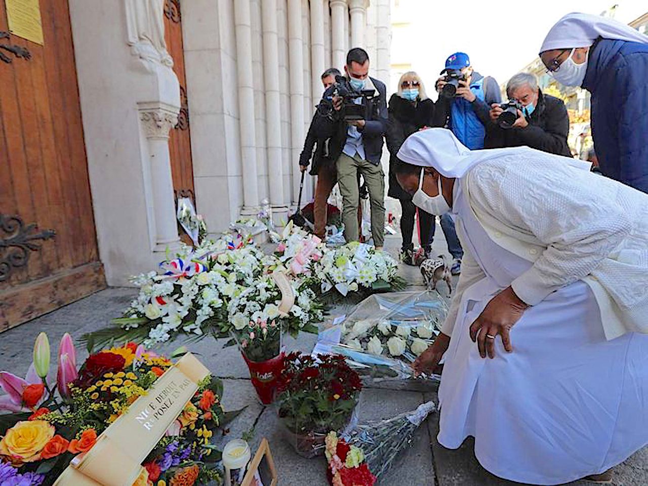 Two nuns lay flowers in front of the Notre-Dame de l'Assomption Basilica in Nice on October 30, 2020 during a tribute to the victims killed by a knife attacker the day before (Image by AFP)
